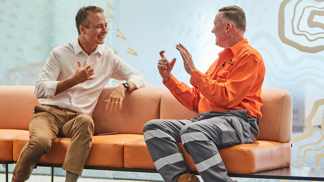 Two Ausgrid employees communicating with sign language outside a meeting room