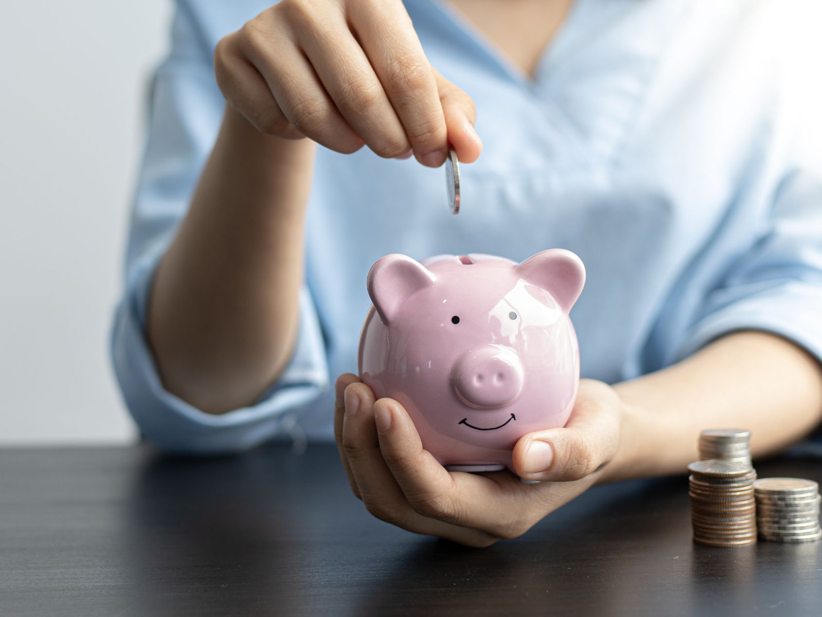 Hand putting coins into piggy bank