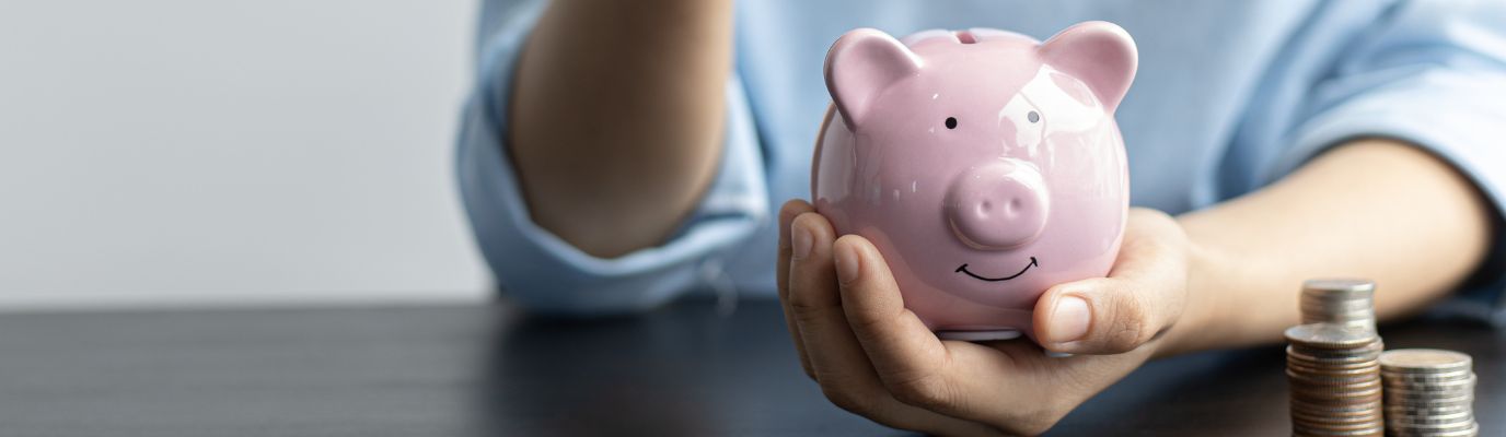 Hands dropping coins into piggy bank