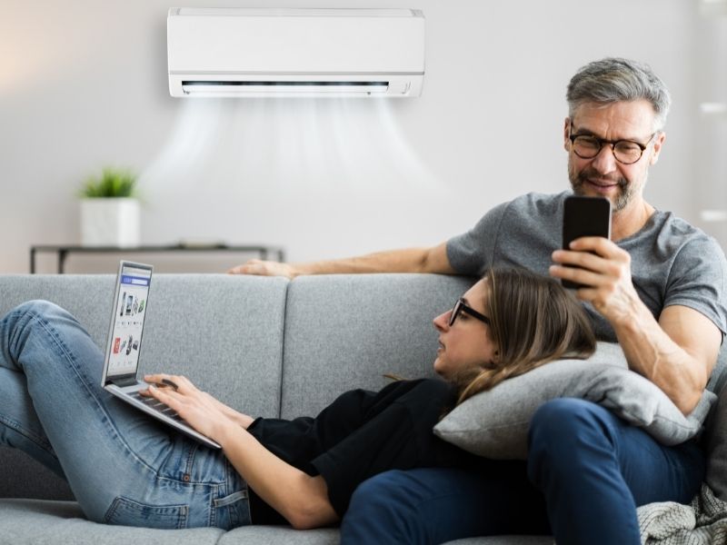 Couple on sofa using air conditioning unit