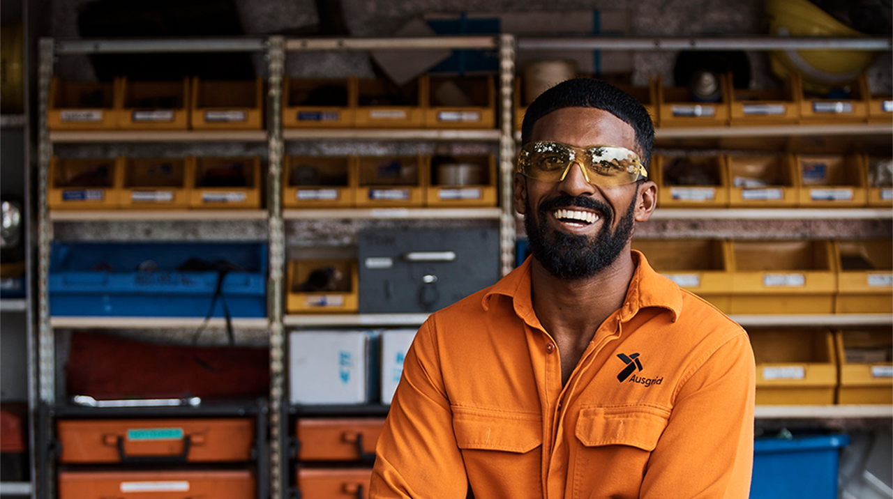 Ausgrid field employee smiling in front of a work bench