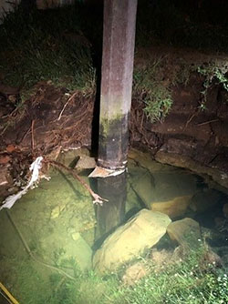 Power pole standing in flooded pit of water