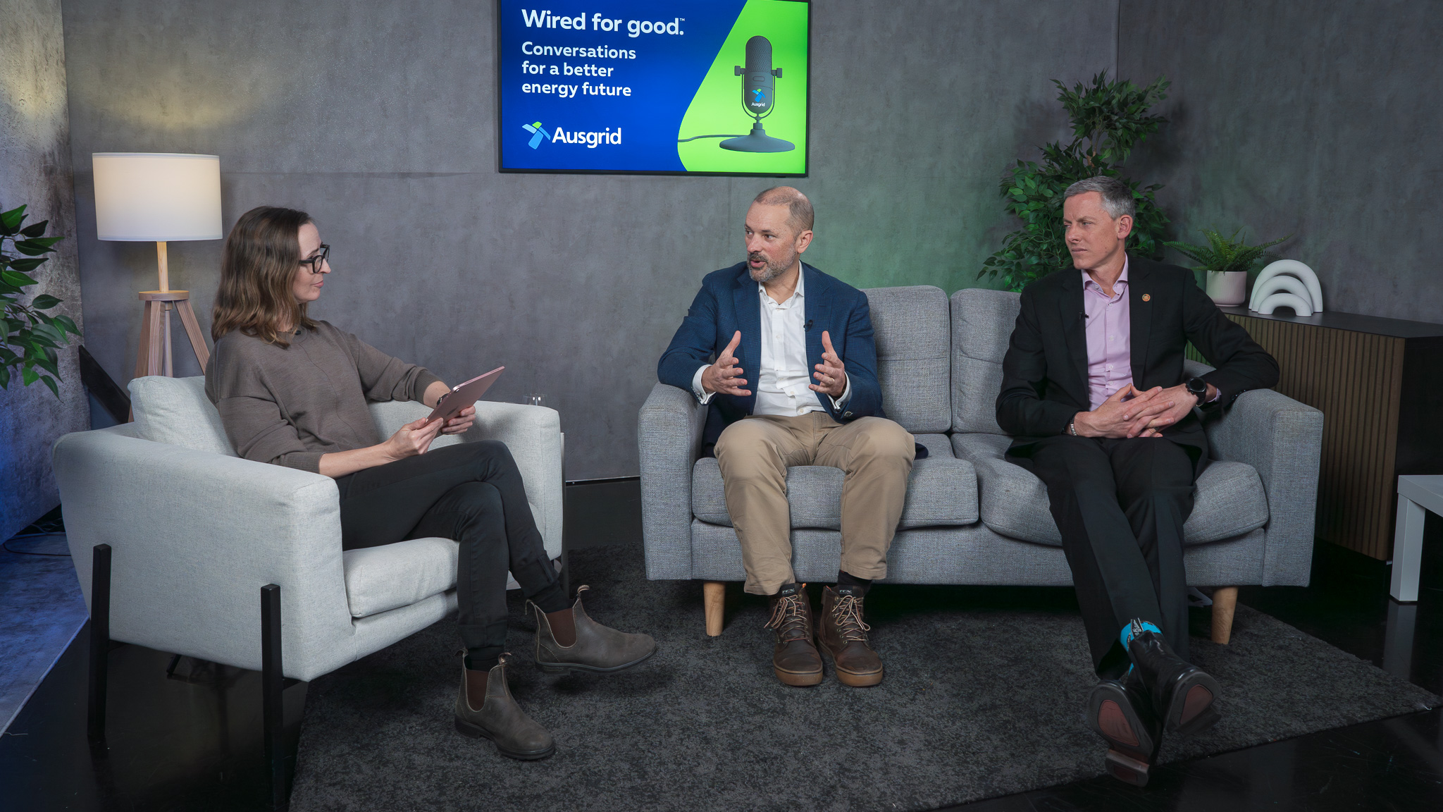 host sarah aubury sitting with steve lewis and sam kernaghan talking in a podcast studio